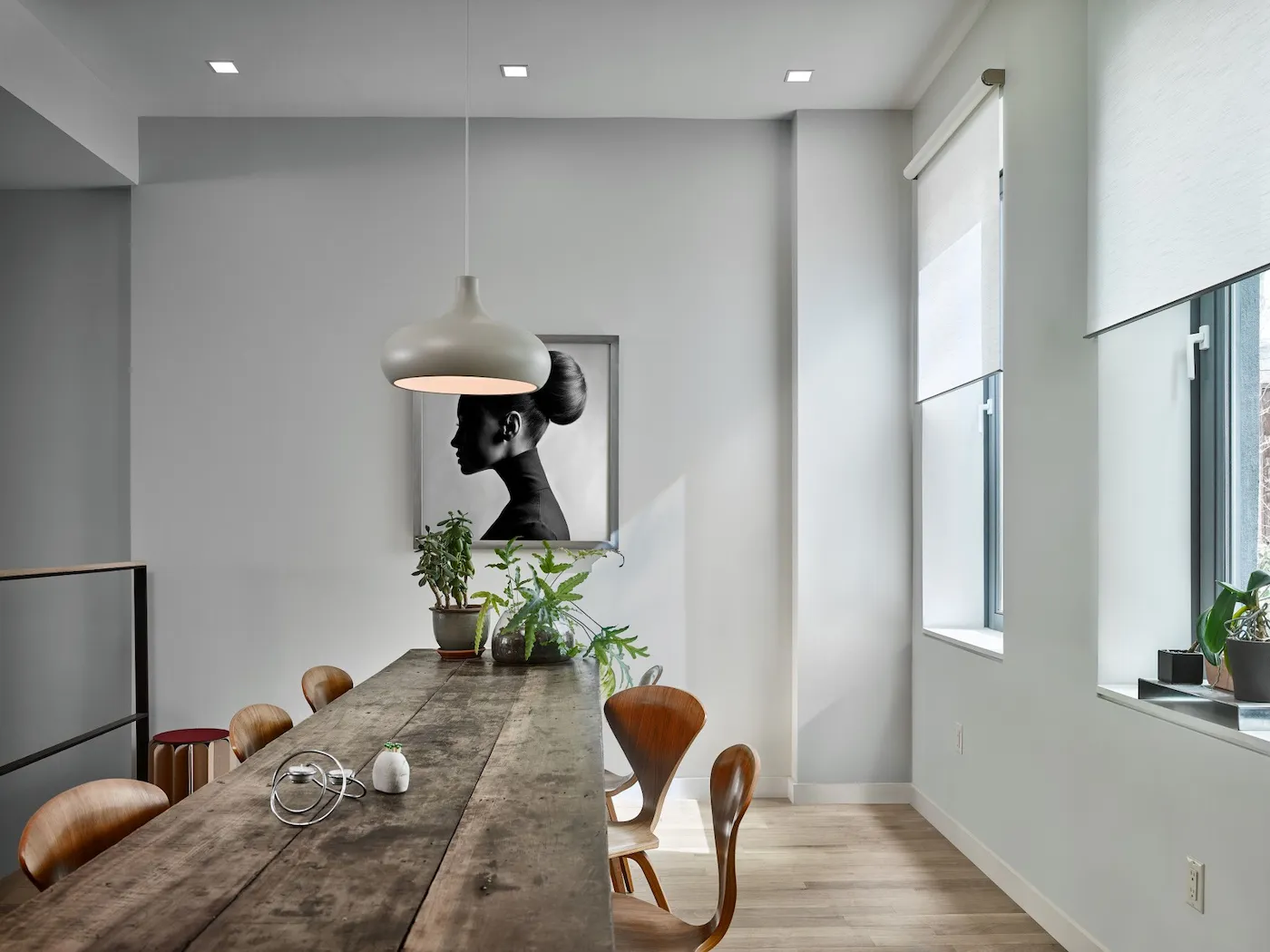 Contemporary dining room with motorized roller shades softly diffusing natural light through tall side windows